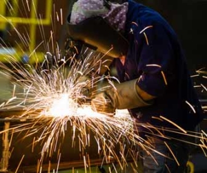 Blue collar worker grinding steel in a factory