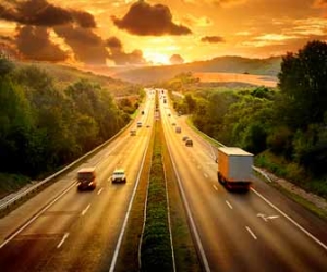 Cars and trucks on highway driving into sunset