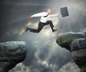 Businessman Jumping Between Gap In Rocks