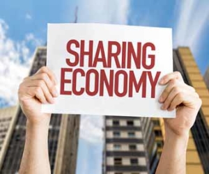 Hands holding sharing economy sign in front of buildings