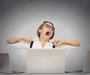 Business woman is bored and yawns in front of laptop