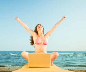 Woman working remotely from laptop on beach