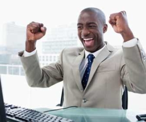 Excited and productive businessman at desk in suit image