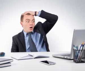 Man in suit is wide eyed and shocked while sitting at desk