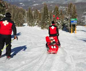 Ski Patrol Taking Injured Skier Down the Mountain in a Sled