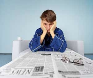 Job seeker staring at newspaper unsuccessfully searching for a job