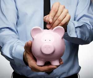 Businessman dropping coins in piggy bank to save money