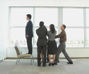 Employees perform trust fall off of chair in office