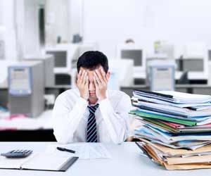 Overworked employee with hands over face sitting at desk