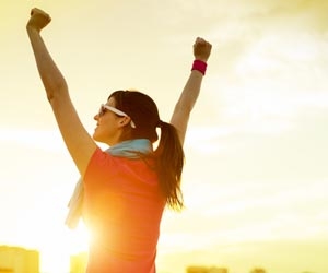 Woman raising arm in sunset after relocating for a job