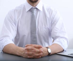 Body of man in suite sitting at desk with hands clasped