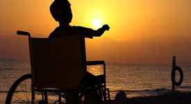 Recreational Therapist Helping Disable Boy Enjoy a Sunset at the Coast