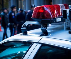 Police car parked in front of group of police officers