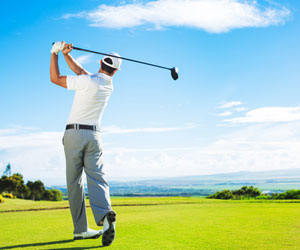 A golfer finishes a swing on a stunning golf course