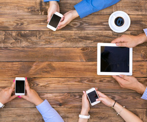 Aerial view of people on smartphone and tablets at table