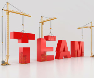 Three cranes working together to build the word "team"