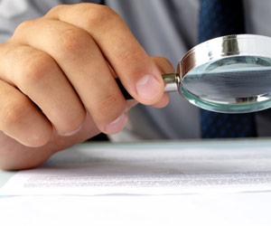 Hand looking at paper using magnifying glass