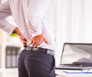 Man standing in front of desk with aching back