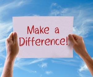 Hands holding a sign that says "make a difference!" against a blue sky