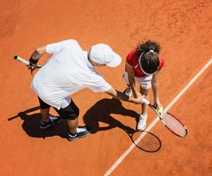 Tennis instructor helps student with tennis serve