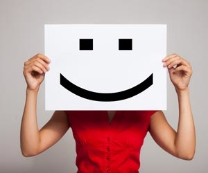 Woman holding a a sign with :) smile over her face